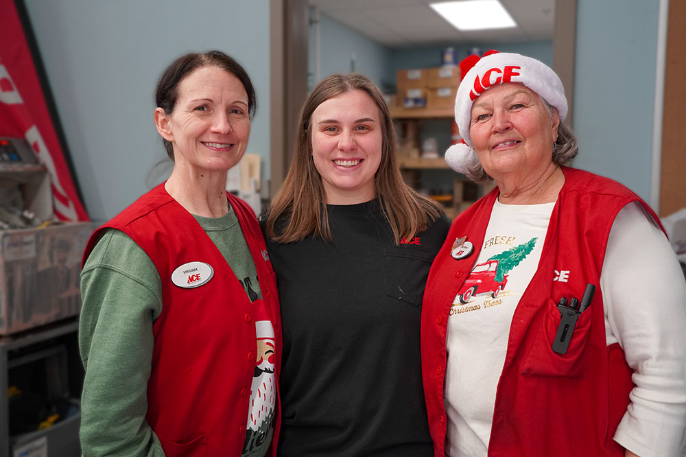 Three Ace Hardware employees with Christmas spirit helping during a kid's club event.